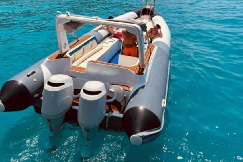 Un motorboat con dos motores fueraborda, cubierta de madera y una persona sentada al timón. 2