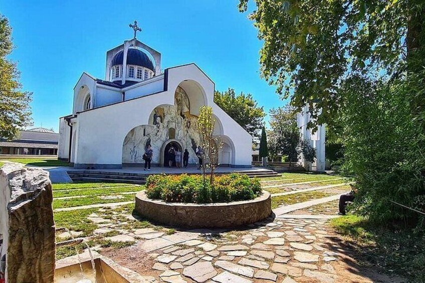 Una iglesia blanca con una cúpula azul, un sendero de piedra y un jardín circular. 3