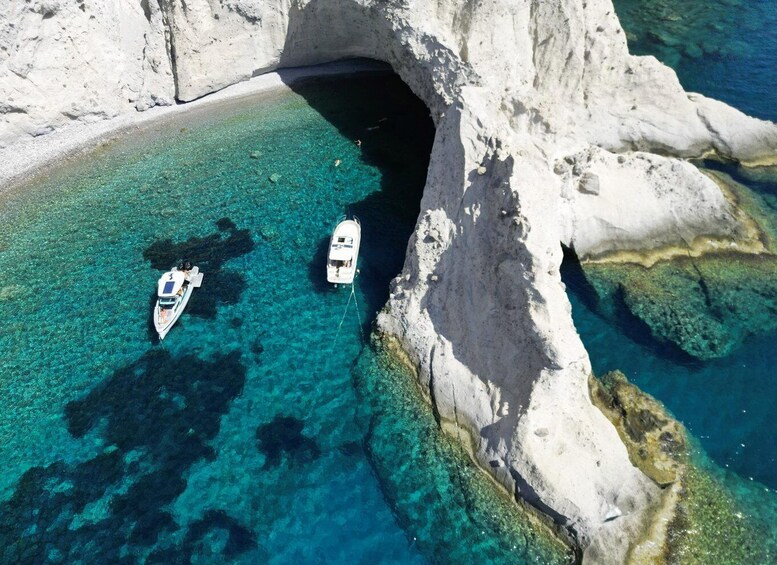 A boat anchored near a rocky coastline with clear turquoise water. 2