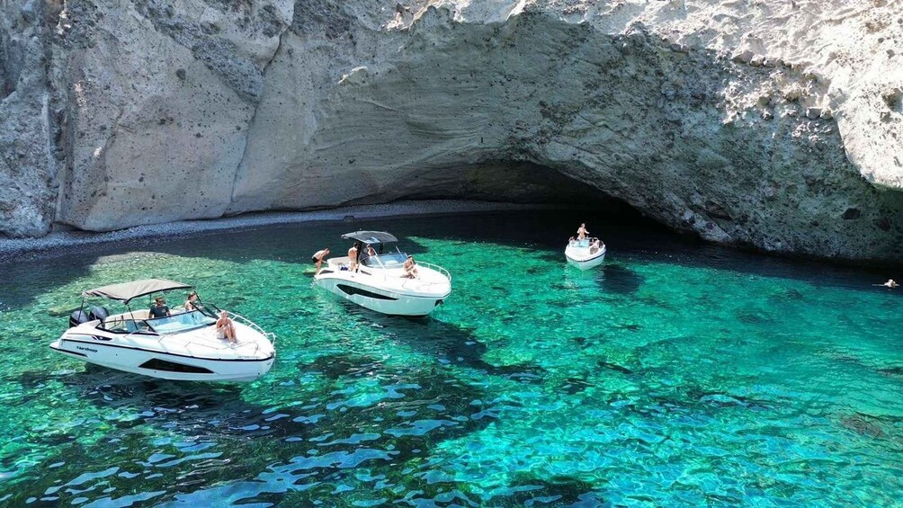 Three boats in a clear blue bay with rocky cliffs. 5