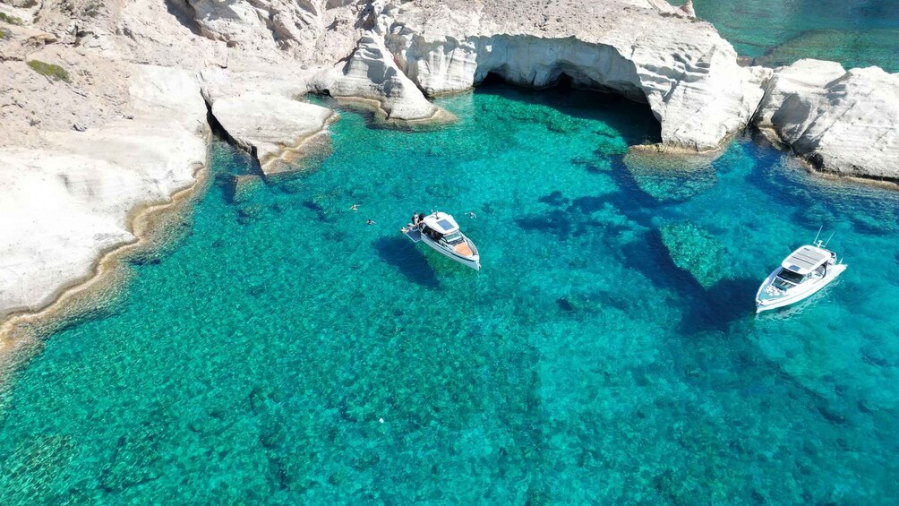 A clear turquoise sea with rocky formations and two boats anchored. 3