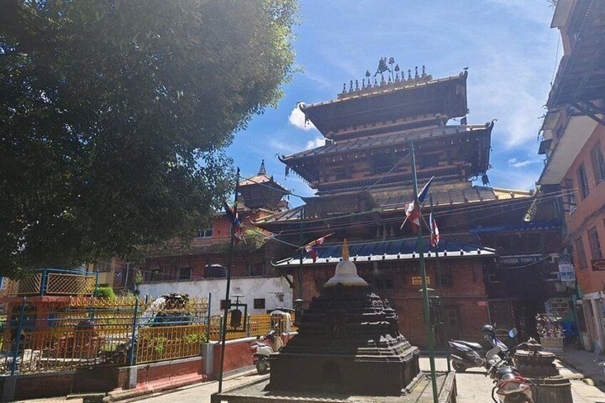 Ett traditionellt pagodtorn med flera våningar, dekorerat med flaggor, omgivet av byggnader och ett träd. 5