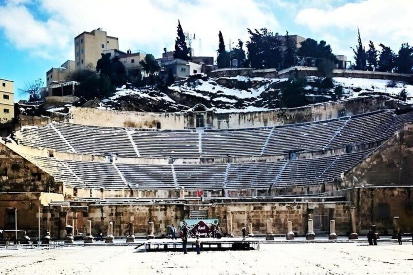 An ancient amphitheater with tiered seating and a backdrop of historic buildings. 4