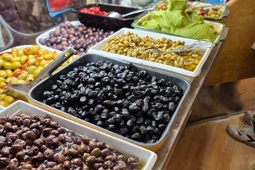 A variety of food items in trays, including olives, beans, and possibly nuts. 4