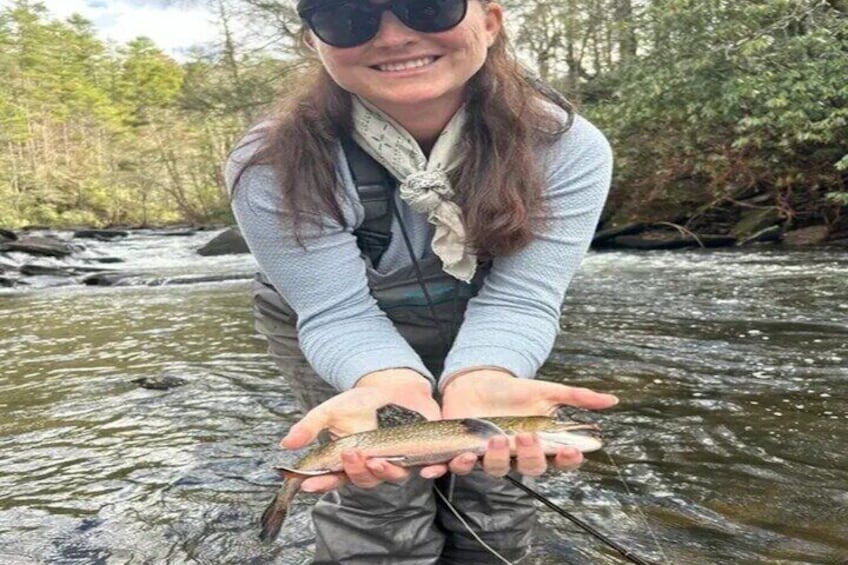 Una persona sosteniendo un pez en un río caudaloso. 4