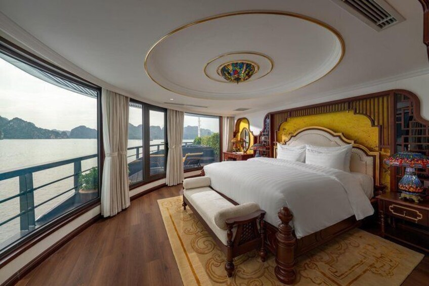 Une chambre à coucher luxueuse, dotée d’un grand lit, offrant une vue sur un plan d’eau et donnant sur un balcon. 2