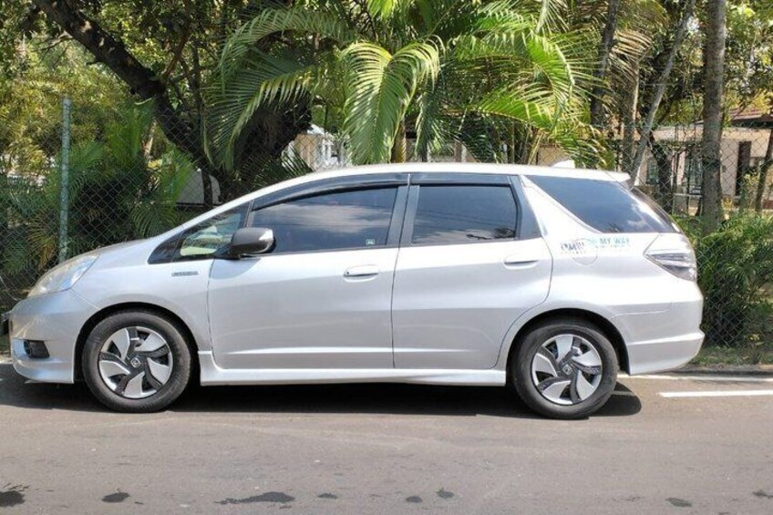 A silver hatchback car parked on a street with palm trees in the background. 1