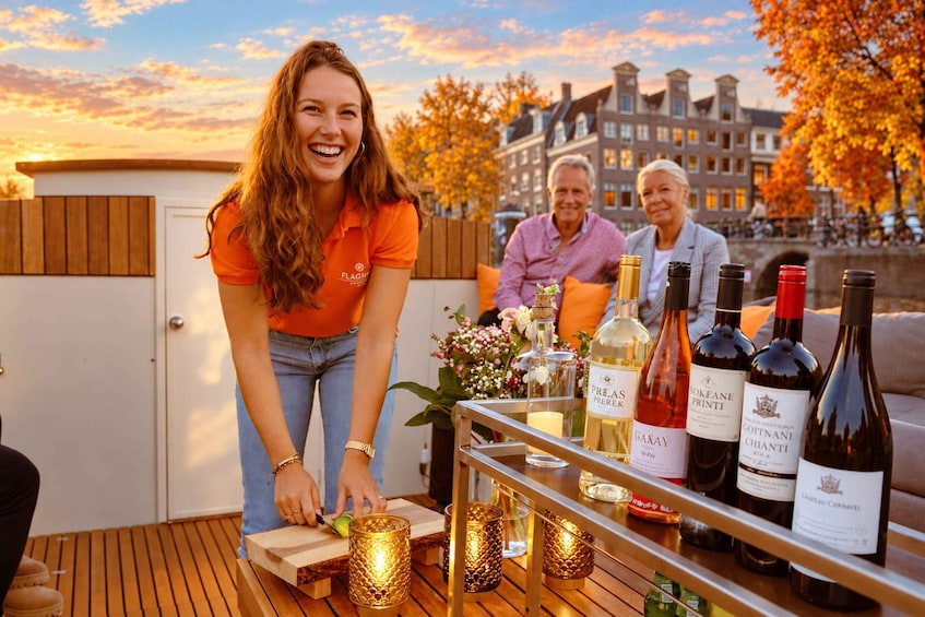 A person serving drinks at an outdoor event with a table of wine bottles and candles. 2