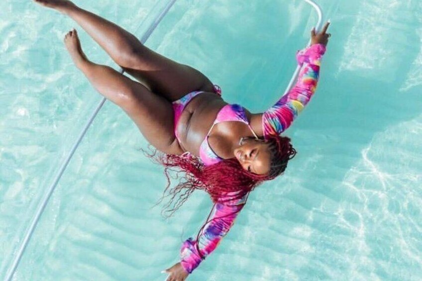 A person floating in a clear blue pool. 4