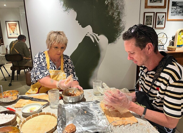 Two people preparing food at a table with various dishes and kitchen utensils. 5