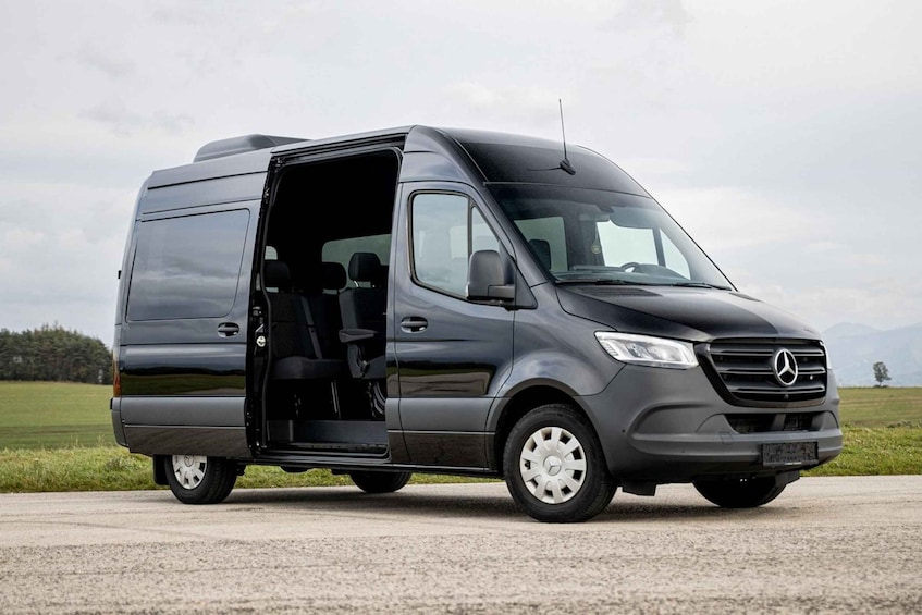 A black Mercedes van parked on a road with its door open, revealing the interior. 2