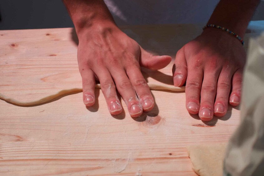 Hands shaping dough on a wooden surface. 1
