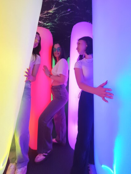 Three people standing in front of illuminated pillars. 5