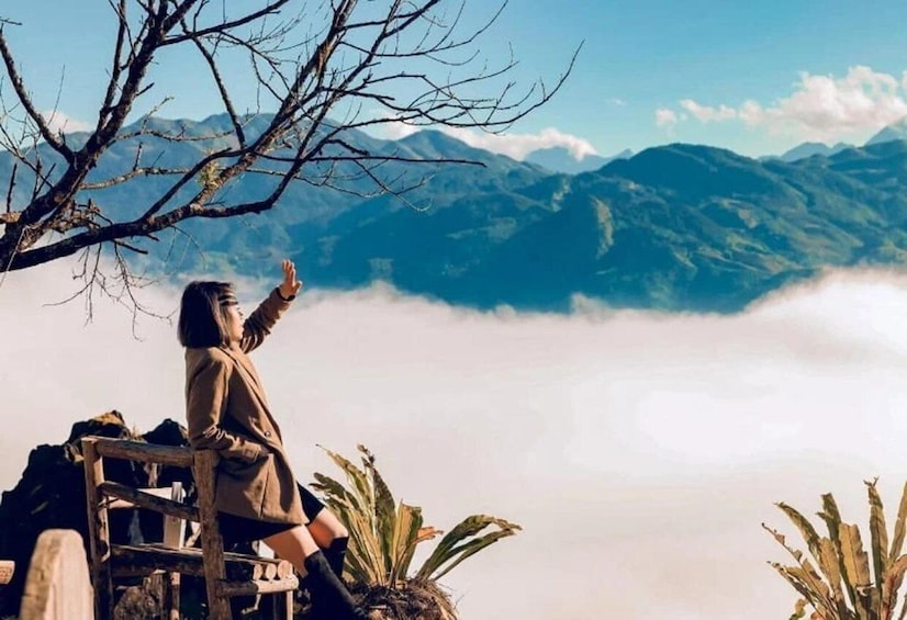 A person sitting on a wooden bench overlooking a mountainous landscape with a view of the clouds below. 2