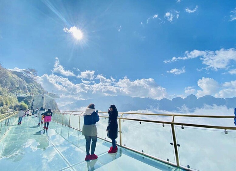 A glass walkway with people observing the mountainous landscape. 1