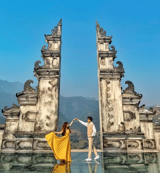 A couple dancing in front of ornate stone gates with a mountainous landscape in the background. 5