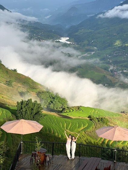 A terrace with two people, a river, and terraced fields in the background. 3