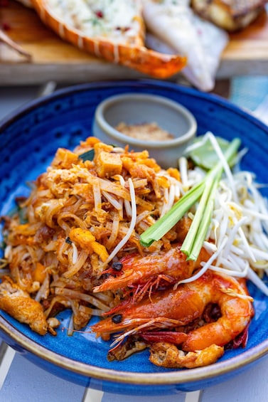 A plate of Pad Thai with shrimp, bean sprouts, and green onions. 2