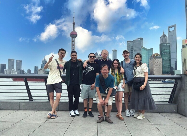 A group of people posing in front of a city skyline with a prominent tower and modern buildings. 1