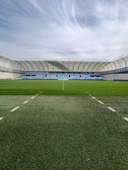 A large stadium with blue seats and a green field. 5