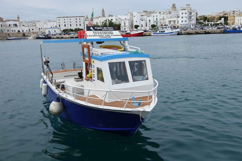 A blue and white boat docked at a harbor with a signboard advertising fishing tours. 1