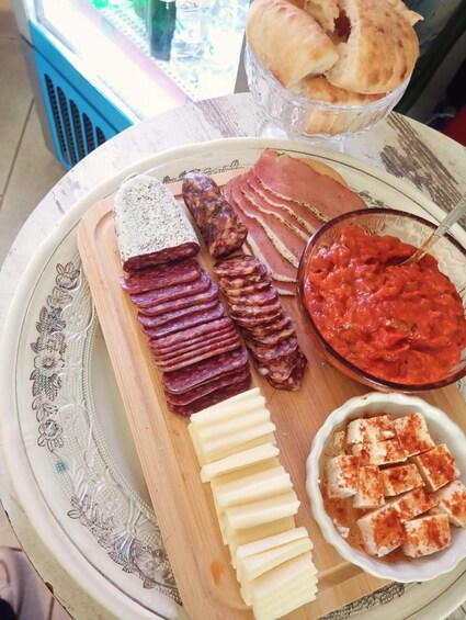 A charcuterie board with various meats, cheeses, and a bowl of tomato sauce. 3