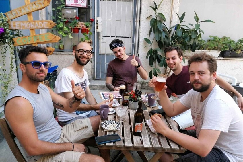 Four people sitting at a wooden table outdoors, enjoying drinks and snacks. 5