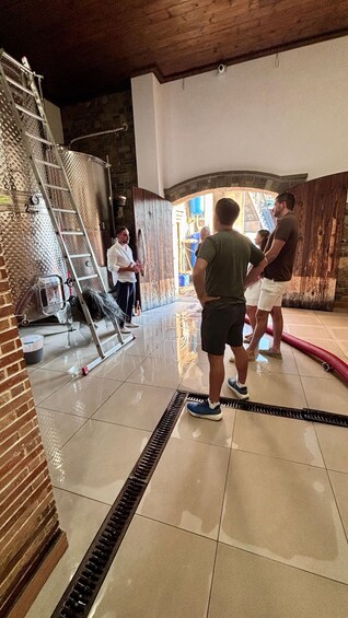 A group of people in a room with a ladder, a metal structure, and a tiled floor. 2
