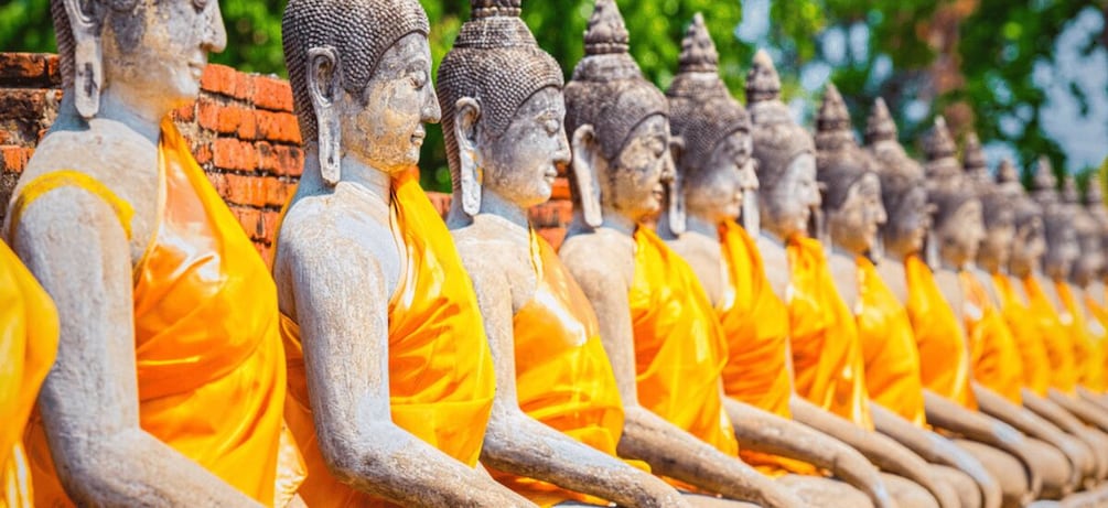 A row of seated Buddha statues with orange robes. 4
