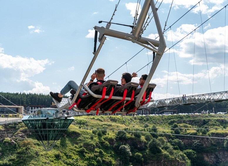 A cable car with passengers in motion, a bridge, and a green landscape with trees. 4