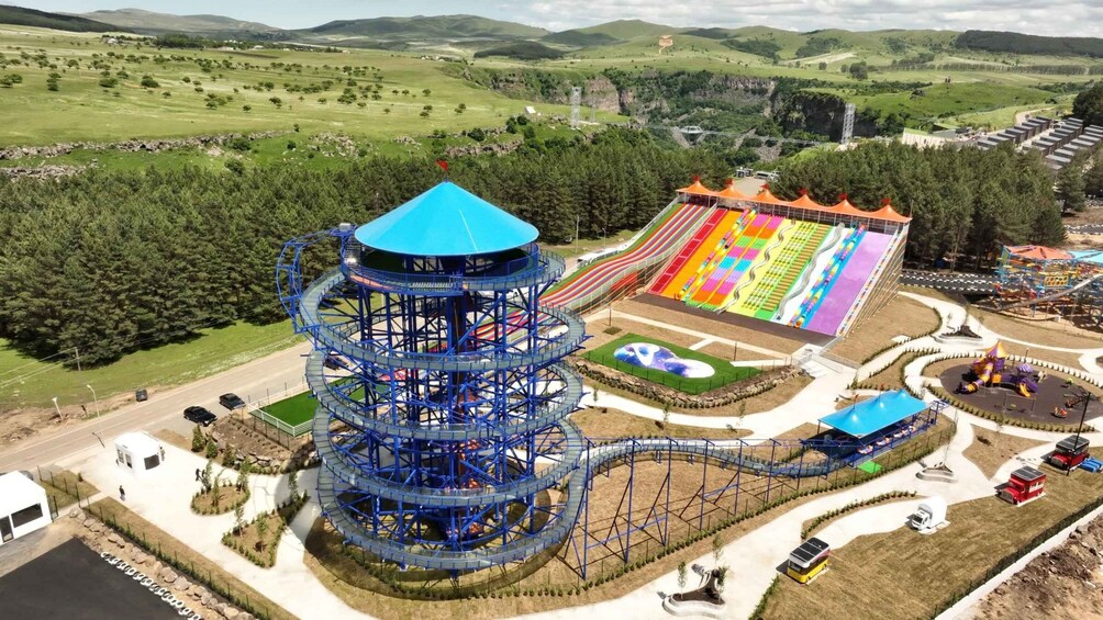 A roller coaster with a blue spiral structure, a colorful water slide, and a playground area. 2