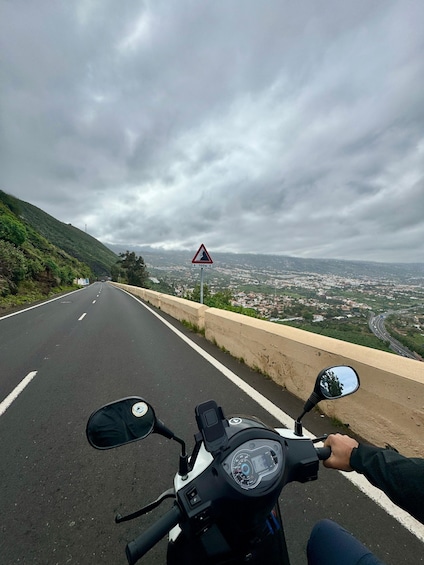 A motorcyclist on a road with a warning sign for a 700m drop ahead. 2