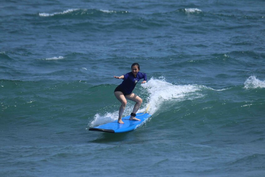 A person surfing on a blue board in the ocean. 2