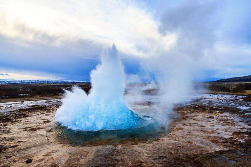 A geyser eruption with steam rising into the sky. 5