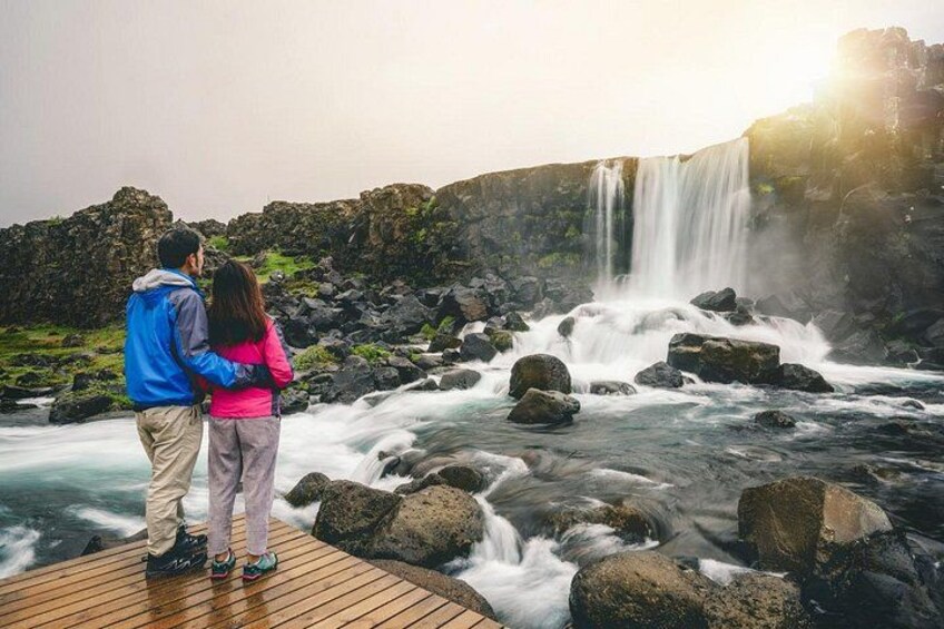 A couple standing on a wooden platform overlooking a waterfall. 2