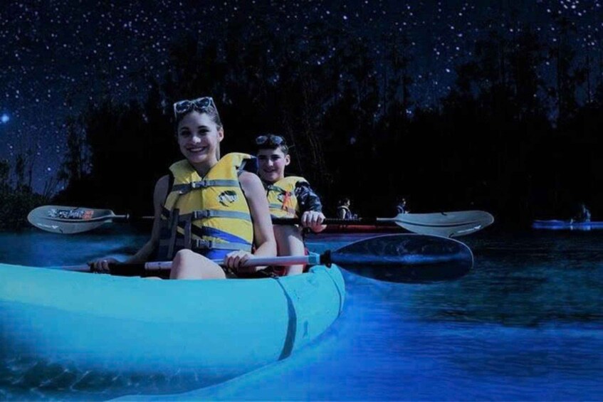 Two people in a kayak on a body of water at night with stars visible in the sky. 2