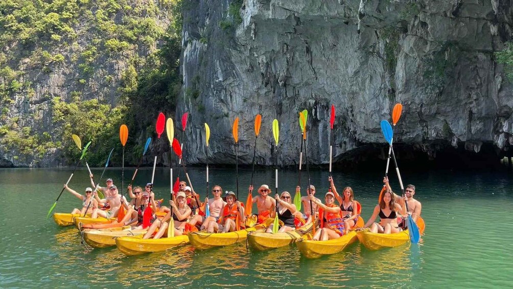 A group of people in yellow kayaks on a calm river with a rocky cliff in the background. 5