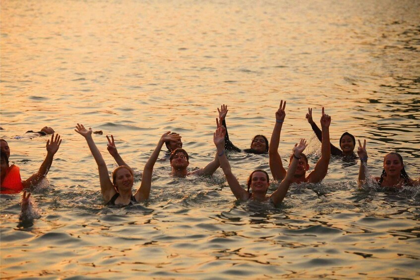 A group of people swimming in a body of water during sunset. 3