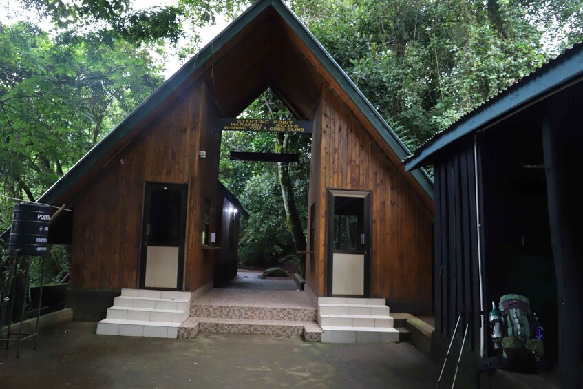 A wooden cabin with a signboard, steps leading to the entrance, and a forested backdrop. 3