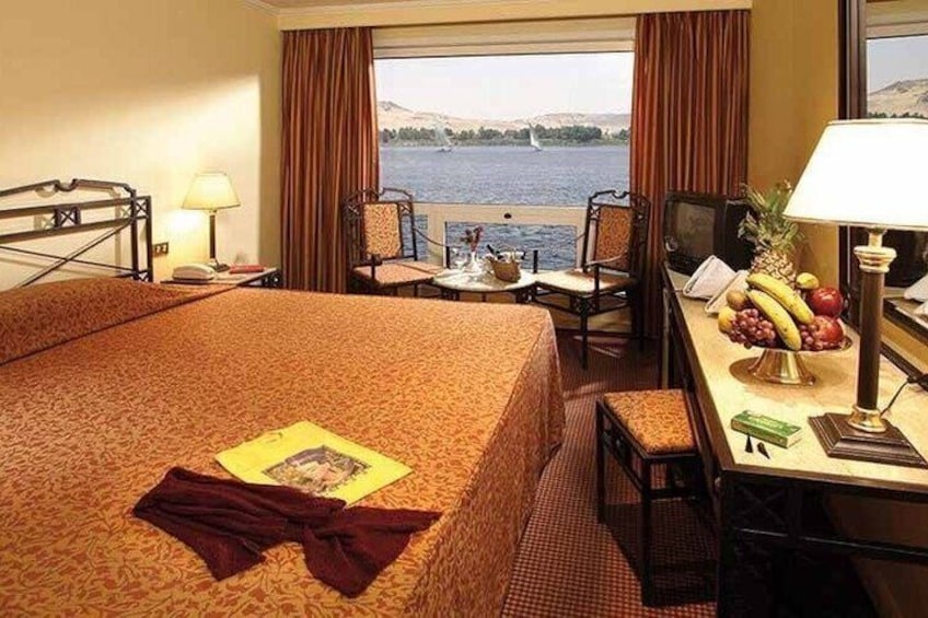 A hotel room with a bed, a desk, a chair, a TV, and a view of the water. 3