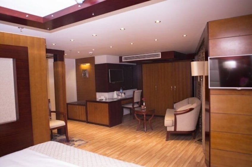 A hotel room with a bed, a desk, a chair, a TV, and wooden cabinets. 5