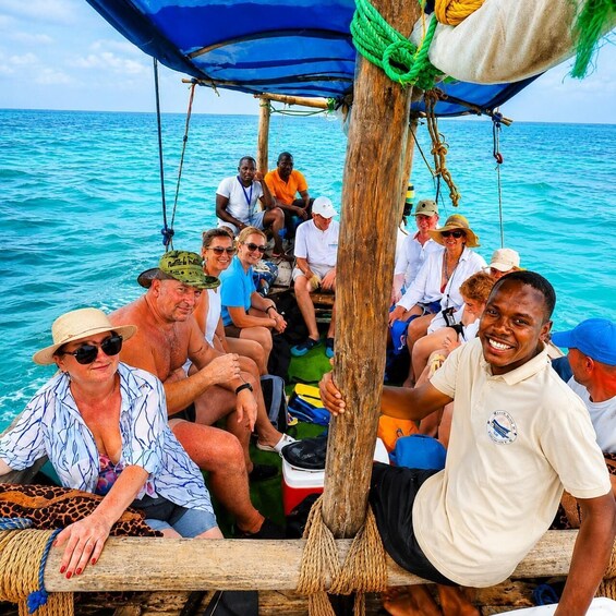 A group of people on a boat with a blue canopy, surrounded by turquoise water. 1