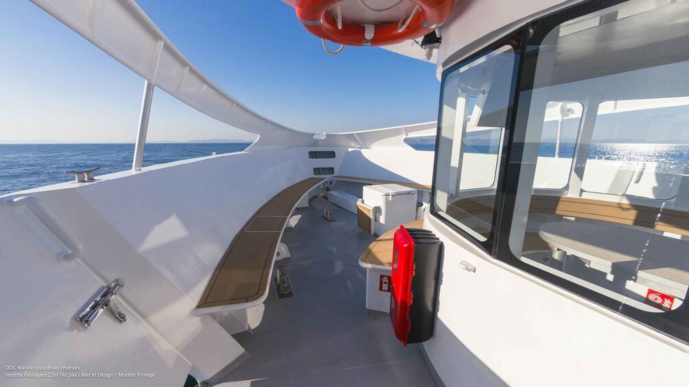 A boat deck with seating, a lifebuoy, and a view of the sea. 2