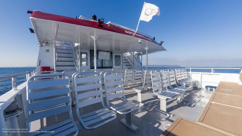 A ferry with a red and white superstructure, metal seating, and a flag. 4