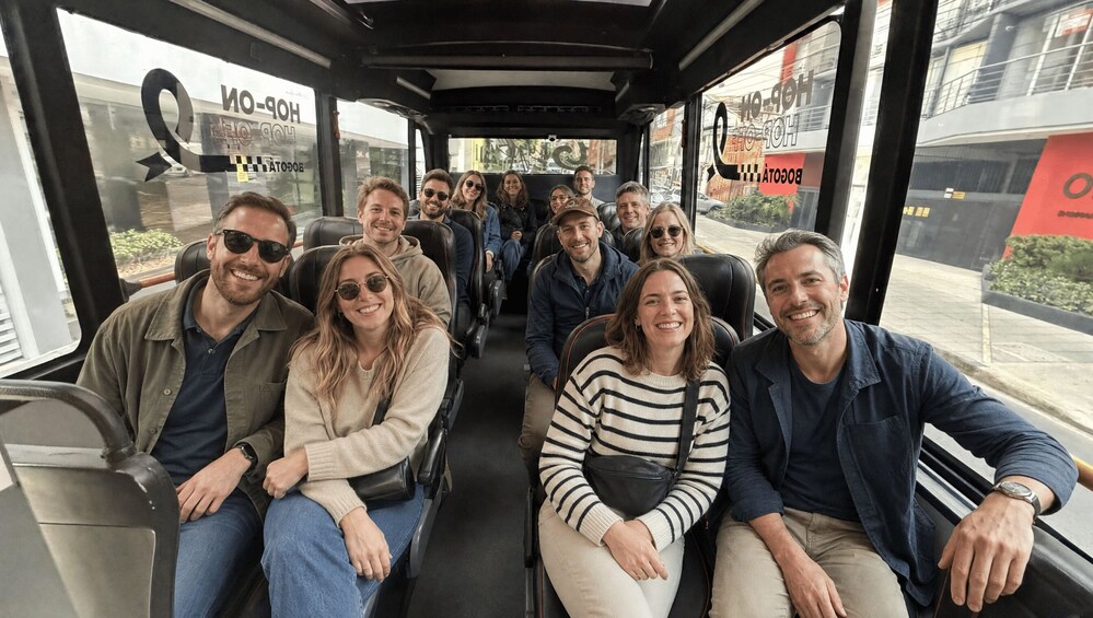 A group of people seated inside a bus with advertisements for 'HOSPITAL' and 'BOGOTÁN' visible through the windows. 4