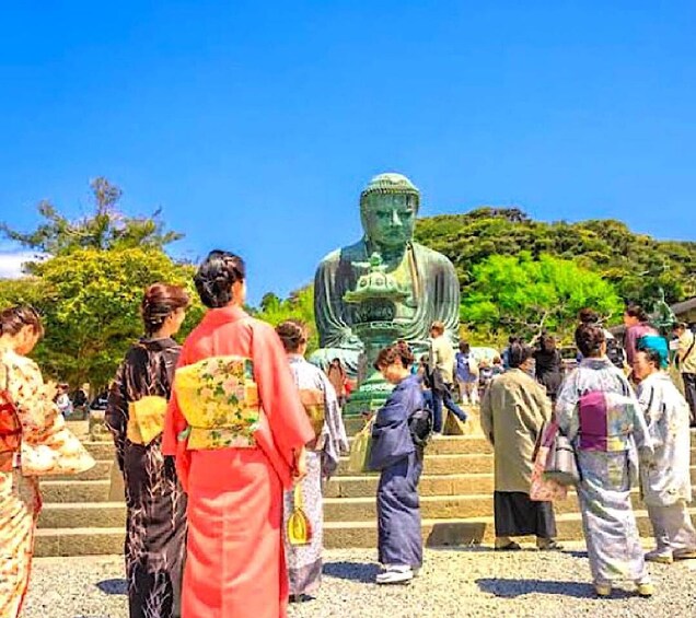 A large Buddha statue surrounded by people in traditional Japanese attire. 2