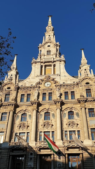 A historic building with ornate architecture, a prominent clock, and a flag. 5