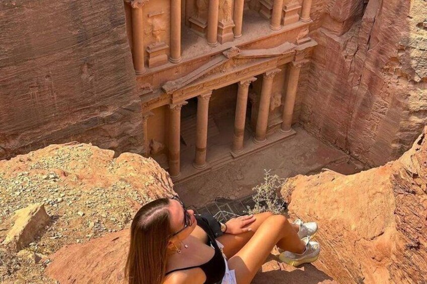 En person som sitter på en sten, med en uthuggen struktur i bakgrunden. 5