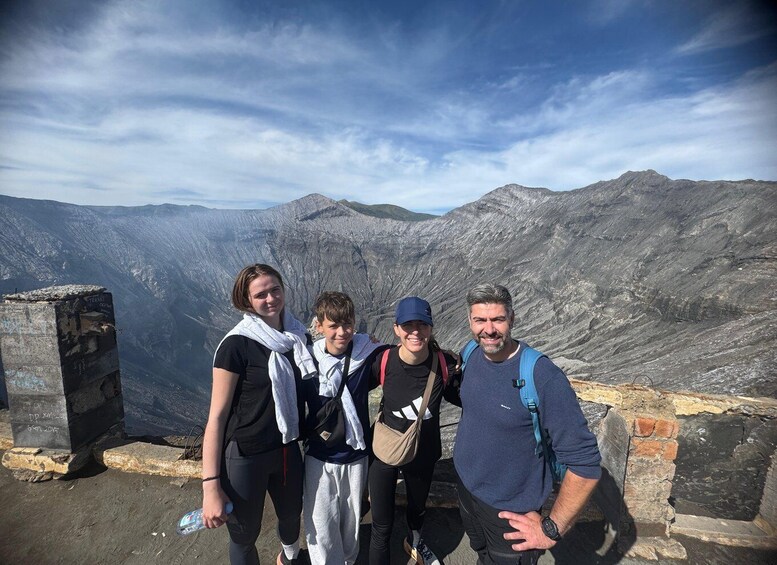 A group of people standing on a rocky outcrop with a mountainous landscape in the background. 2