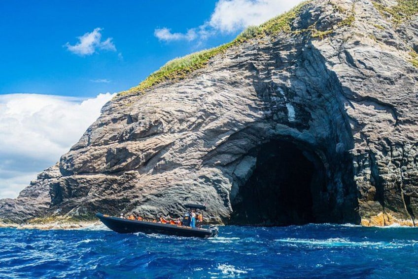 Un bote cerca de una costa rocosa con la entrada de una cueva. 4